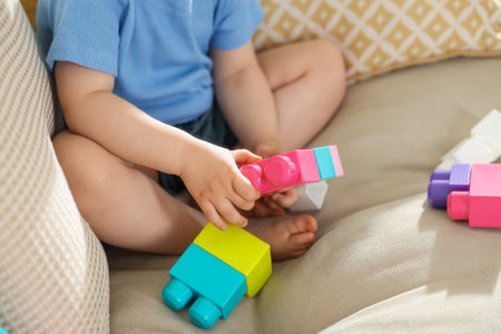 Cute little child playing with building bricks on sofa at home, closeupの写真素材