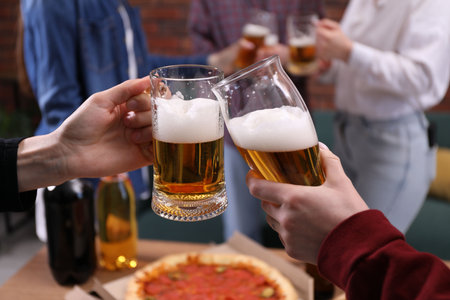 Friends clinking glasses of beer at table, closeupの写真素材