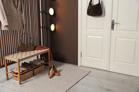 Stylish bag hanging on door and different shoes in hallwayの写真素材