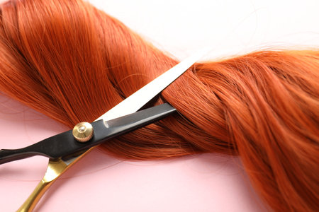 Hair strands and scissors on light pink background, closeupの写真素材