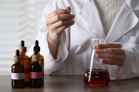 Professional perfumer developing luxury perfume at wooden table in laboratory, closeupの写真素材