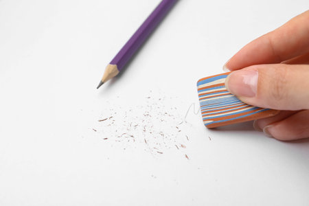 Woman erasing pencil strokes from paper sheet, closeup