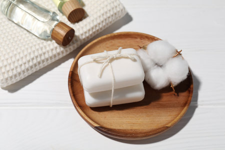 Soap bars, cosmetic products, towel and cotton flower on white wooden table, above viewの写真素材