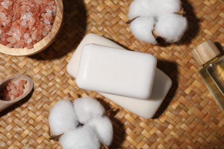 Soap bars, cosmetic products and cotton flowers on wicker mat, flat layの写真素材