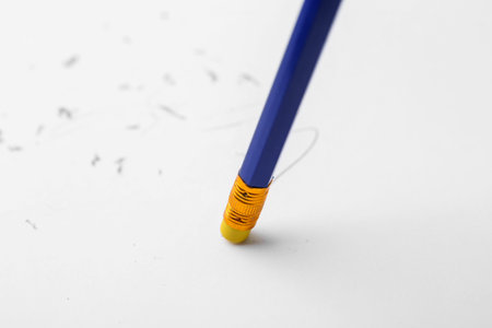Graphite pencil with eraser on paper sheet, closeup