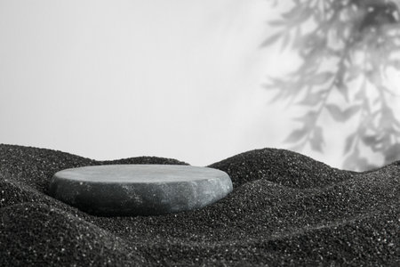Podium for product presentation. Stone on black sand against white background with shadow. Stylish promotion posterの写真素材