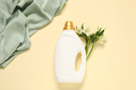 Bottle of fabric softener, flowers and green cloth on beige background, flat layの写真素材