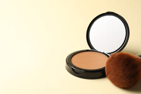 Open face powder with mirror and brush on beige background, closeup. Space for textの写真素材