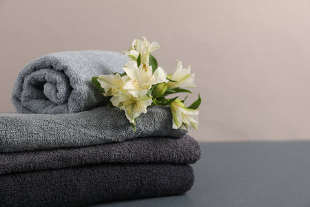 Soft towels and lilies on gray table against beige background, closeup. Space for textの写真素材