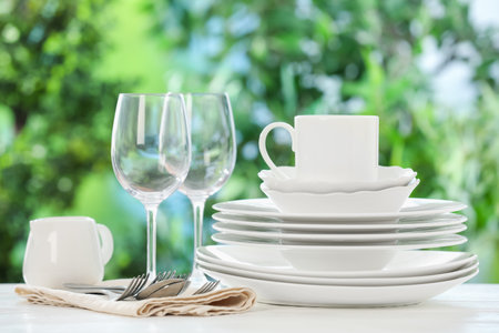 Different clean dishes on white table against blurred green backgroundの写真素材