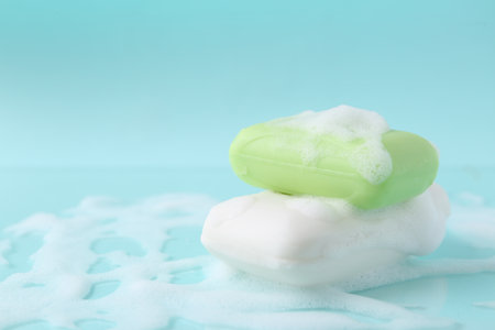 Soap bars with foam on light blue background, closeup. Space for textの写真素材