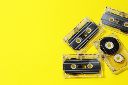 Audio cassettes with magnetic tapes on yellow background, above view. Space for textの写真素材