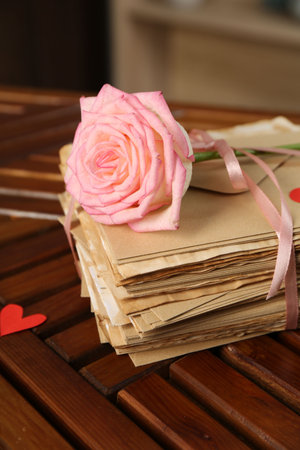 Stack of love letters, rose flower and paper heart on wooden table indoors, closeupの写真素材