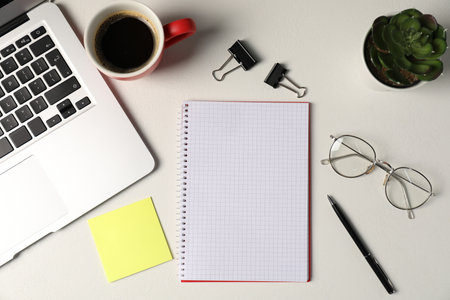 Notebook, sticky note, pen, floral decor, glasses, coffee and laptop on white table, flat layの写真素材