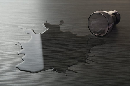 Overturned glass and spilled water on wooden tableの写真素材