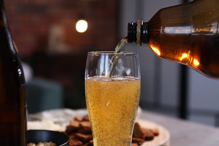 Pouring beer into glass at table, closeup