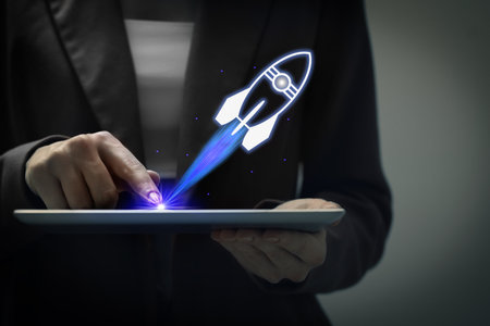 Business, successful startup. Woman using tablet computer against dark background, closeup. Rocket launching from deviceの写真素材