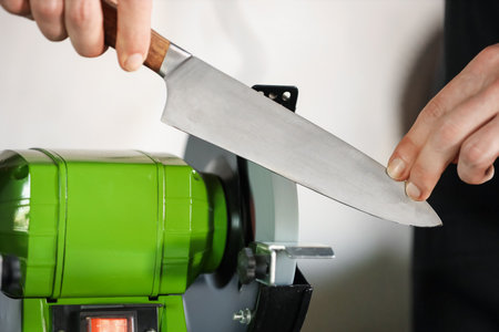 Man sharpening knife with bench grinder indoors, closeupの写真素材