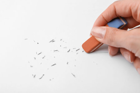 Woman erasing pencil strokes from paper sheet, closeupの写真素材