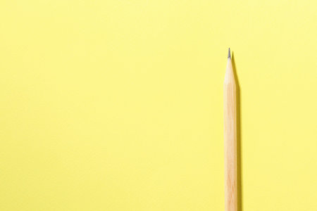 One graphite pencil on yellow background, top view. Space for textの写真素材