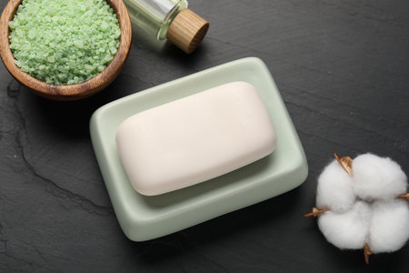 Soap bar, cosmetic products and cotton flower on black table, flat layの写真素材