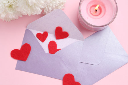 Love letters, red hearts, burning candle and flowers on pink background, flat layの写真素材