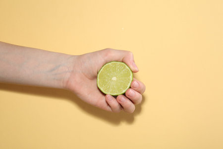 Woman with lime on yellow background, closeupの写真素材