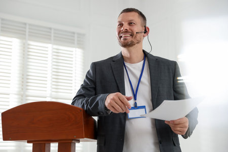 Man giving public speech with microphone at lectern indoorsの写真素材