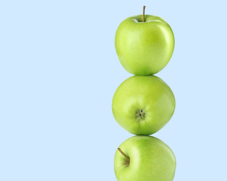 Green apples stacked on top of each other against light blue background. Balanceの写真素材