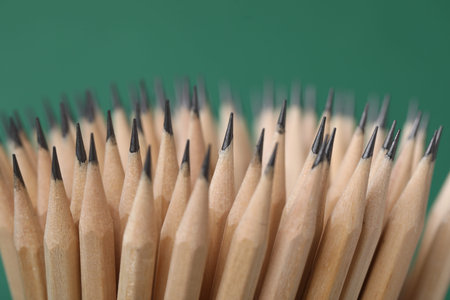 Many graphite pencils on green background, closeup