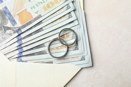 Two silver wedding rings, dollar banknotes and envelope on white table, top view. Space for textの写真素材