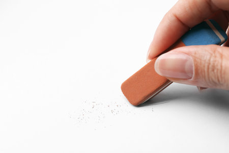 Woman using eraser on white paper, closeup. Space for textの写真素材