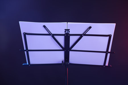 Stand with music sheets in neon lights on dark background, closeupの写真素材