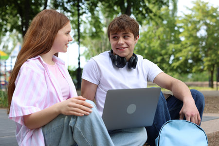Teenage girl and boy with laptop outdoorsの写真素材