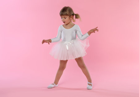 Cute little girl dancing on pink backgroundの写真素材