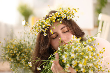 Portrait of beautiful woman with chamomile flowers indoorsの写真素材