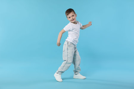 Happy little boy dancing on light blue background. Space for textの写真素材