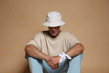Fashionable portrait of handsome man in stylish outfit on brown background