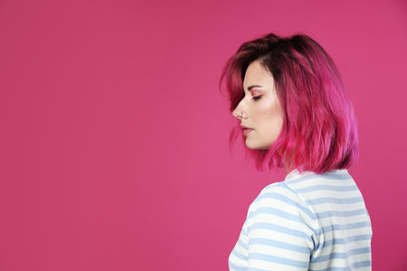 Beautiful woman with bright dyed hair on pink background, space for textの写真素材