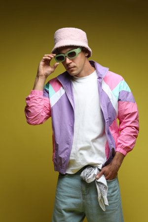 Fashionable portrait of handsome man in stylish outfit on olive background