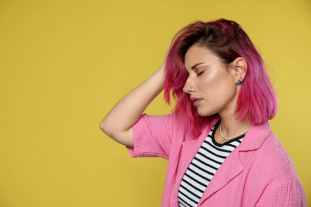 Beautiful woman with pink dyed hair on yellow background, space for textの写真素材