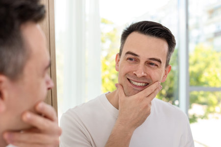 Smiling man after shaving near mirror at homeの写真素材