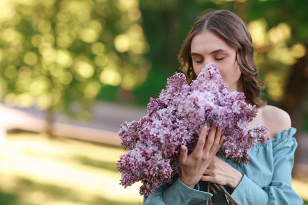 Beautiful woman with bouquet of lilac flowers outdoors in morning. Space for textの写真素材