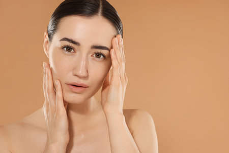 Beautiful woman after spa treatment on beige background, closeup. Space for textの写真素材