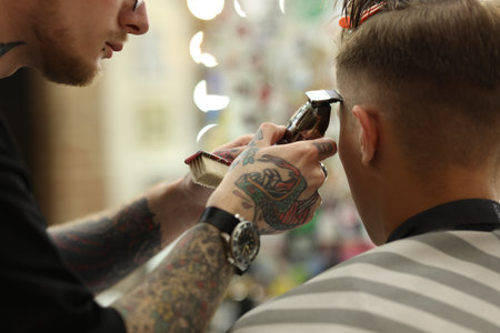 Professional barber making stylish haircut in barbershop, closeupの写真素材