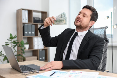 Banker waving money at table in officeの写真素材