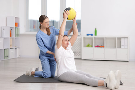 Doctor and patient exercising with medicine ball in clinic