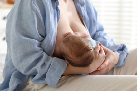 Mother breastfeeding her newborn baby indoors, closeup