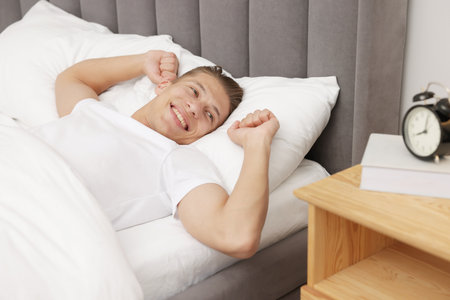 Man lying in comfortable bed at homeの写真素材