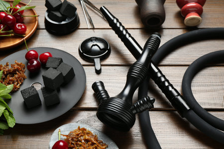 Traditional hookah parts, tobacco, charcoal cubes, cherries and mint on wooden table